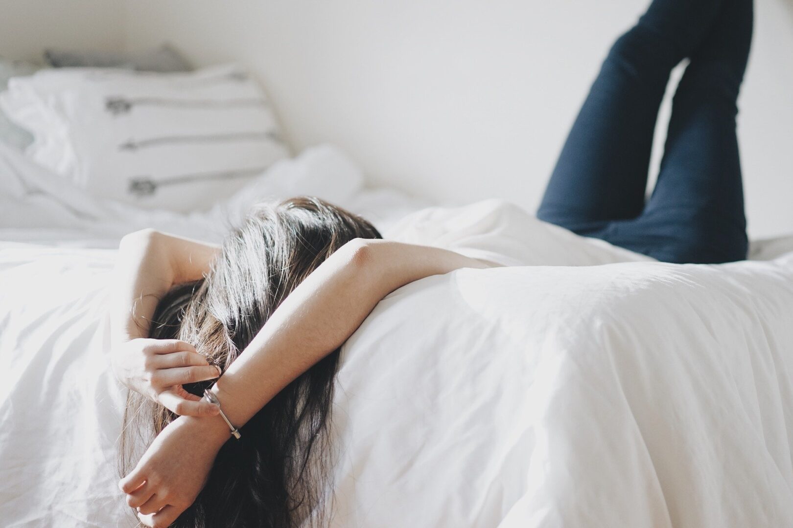 Mulher deitada na cama com as pernas para cima 